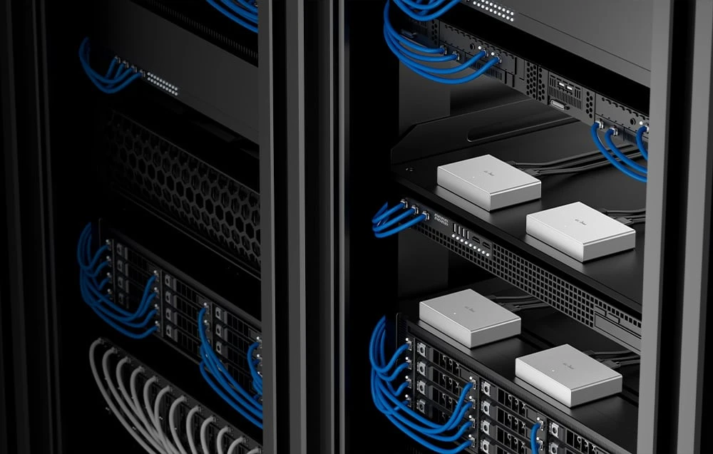 Mai multe comutatoare KVM argintii dispuse în rack-uri negre de servere, cu cabluri albastre