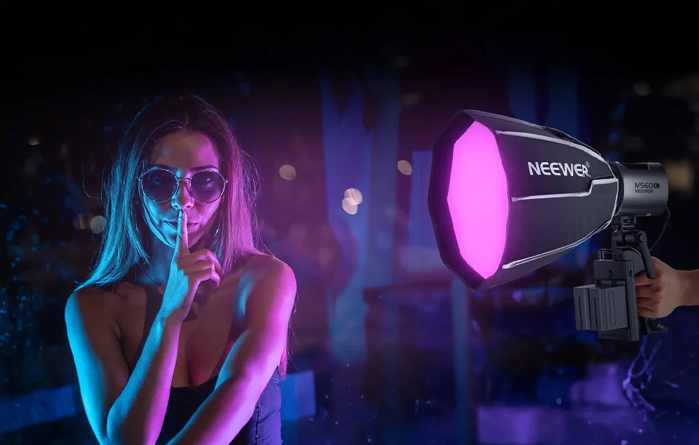 Un model care poartă ochelari, iluminat de lumina roz și albastră provenită de la o softbox Neewer în timpul unei ședințe foto nocturne.