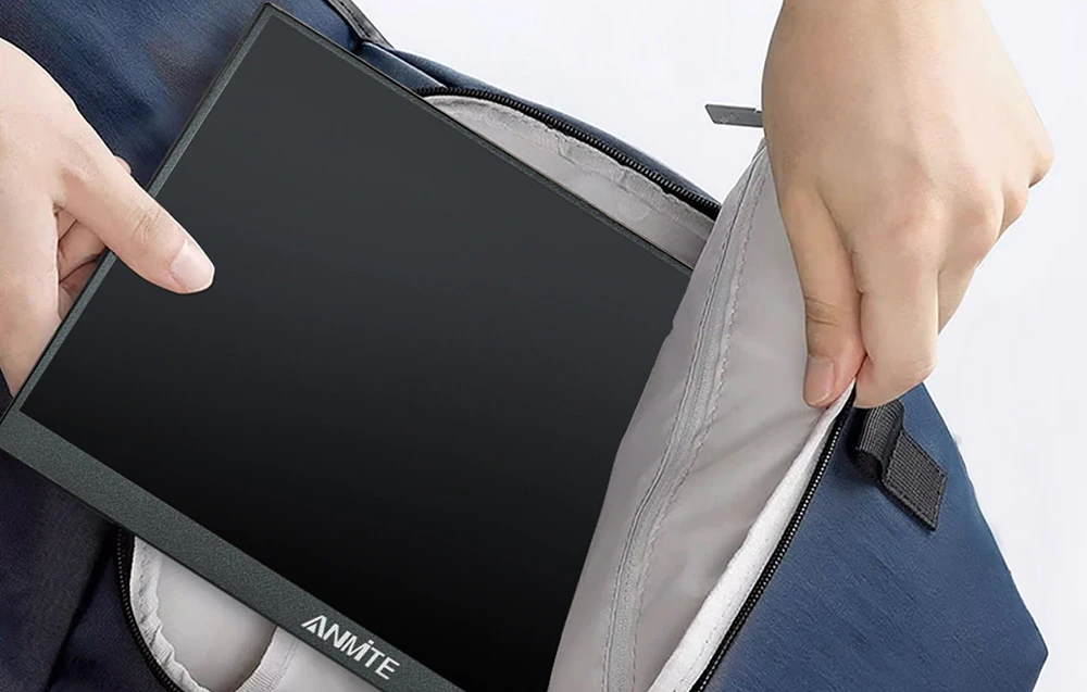 Mâini care introduc un monitor portabil plat în compartimentul deschis al unui rucsac albastru închis.