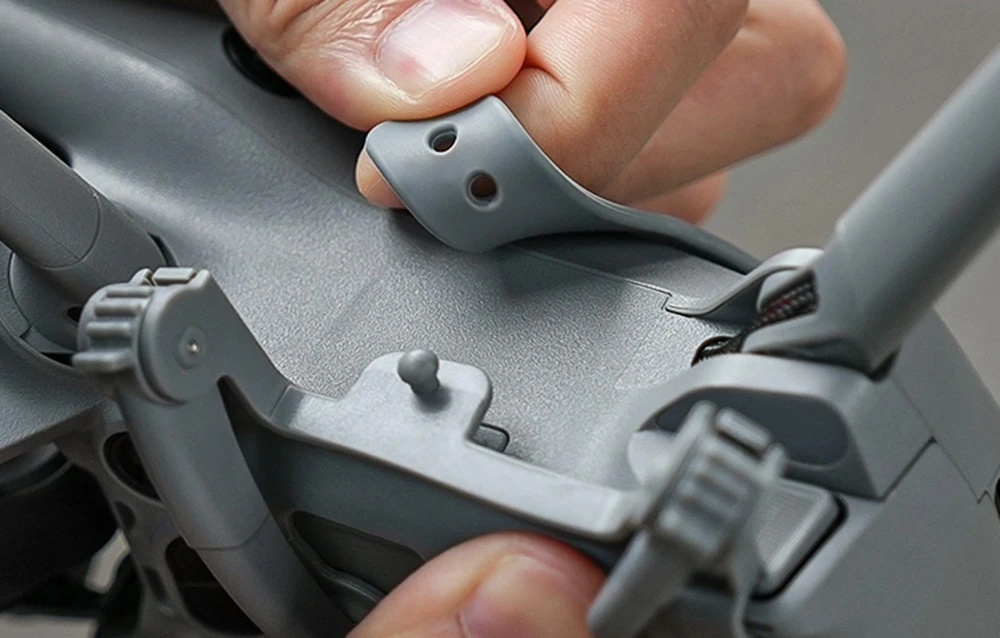 Prim plan al mâinilor care pun cureaua de siguranță din cauciuc pe drona DJI Mini 5 Pro