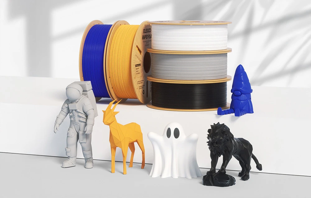 Bobine colorate de filament 3D lângă figurine de astronaut, cerb, fantomă, rachetă și leu