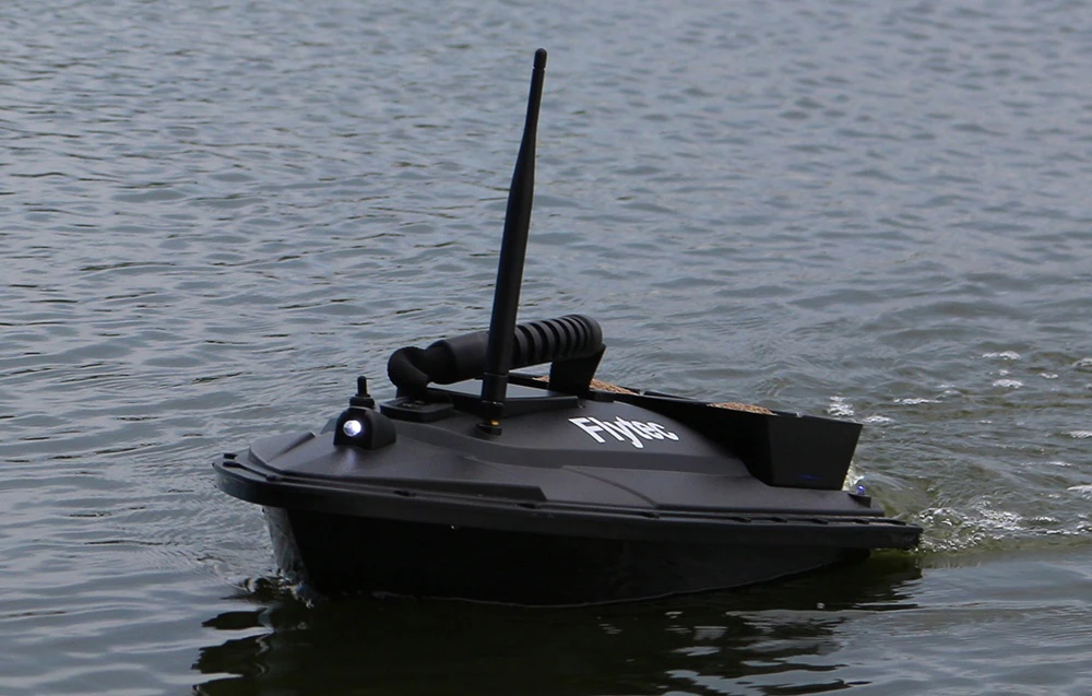 Barca de momeală Flytec neagră cu antenă plutind pe un lac sau râu