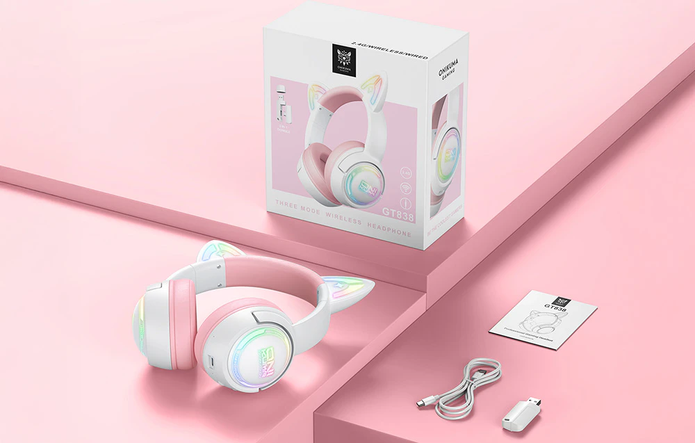 Cutie, cablu USB, adaptor, manual de utilizare și căști Onikuma așezate pe o masă roz