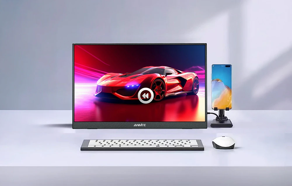 O stație de lucru cu un monitor pe care se vede o mașină roșie, o tastatură, un mouse și un smartphone.
