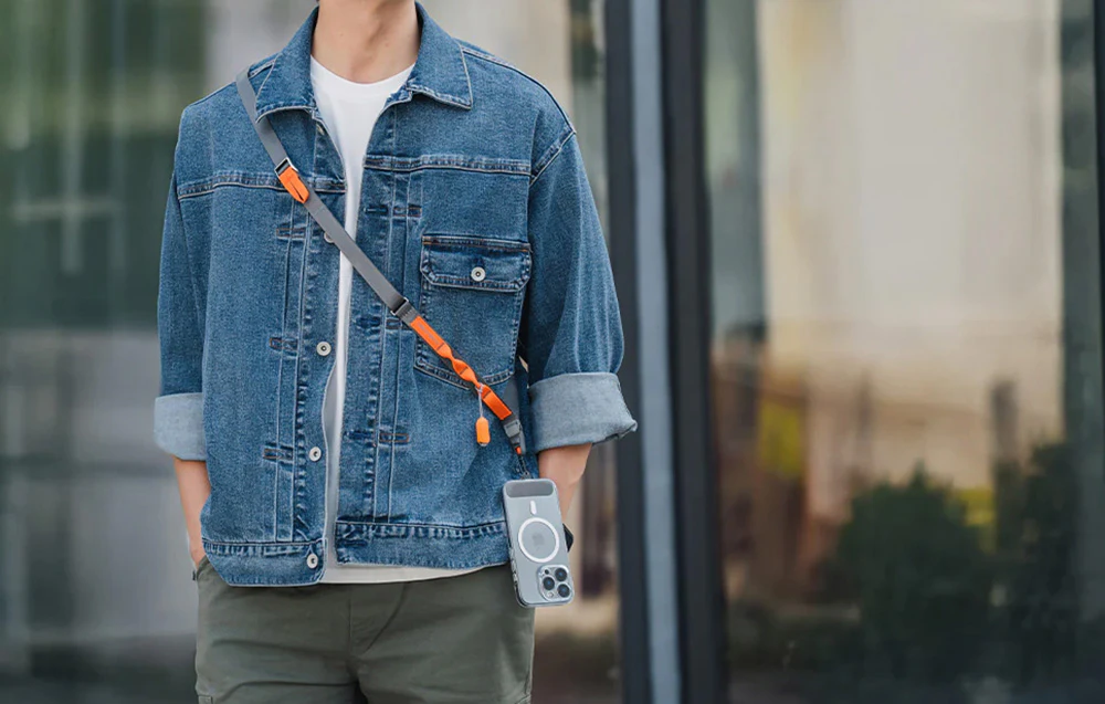 Un bărbat purtând o jachetă din denim și o curea de gât PGYTECH, la care este montat un smartphone