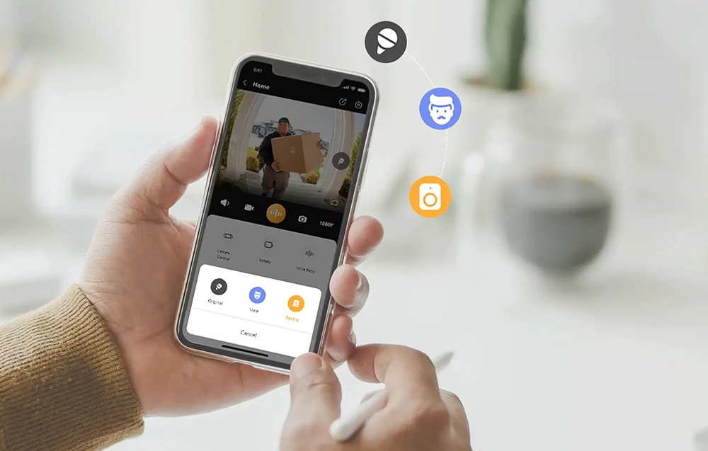 Mâini ținând un smartphone cu aplicația și o previzualizare a livratorului; sunt vizibile pictogramele pentru schimbarea vocii într-una de robot sau de bărbat