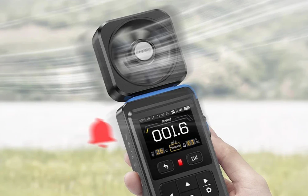 O mână ținând un anemometru FNIRSI FAM-02 pornit, cu rotorul în rotație, pe fundalul unui peisaj estompat