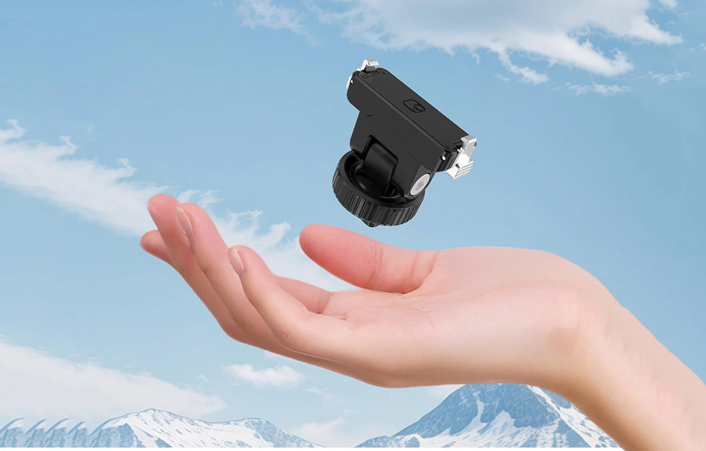 Adaptor magnetic Puluz plutind peste o mână deschisă pe un fundal de munți și cer