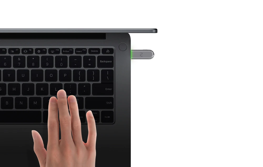 Laptopul cu tastatură de culoare închisă are un dispozitiv metalic cu un LED verde conectat la el, iar o mână plutește în apropiere.