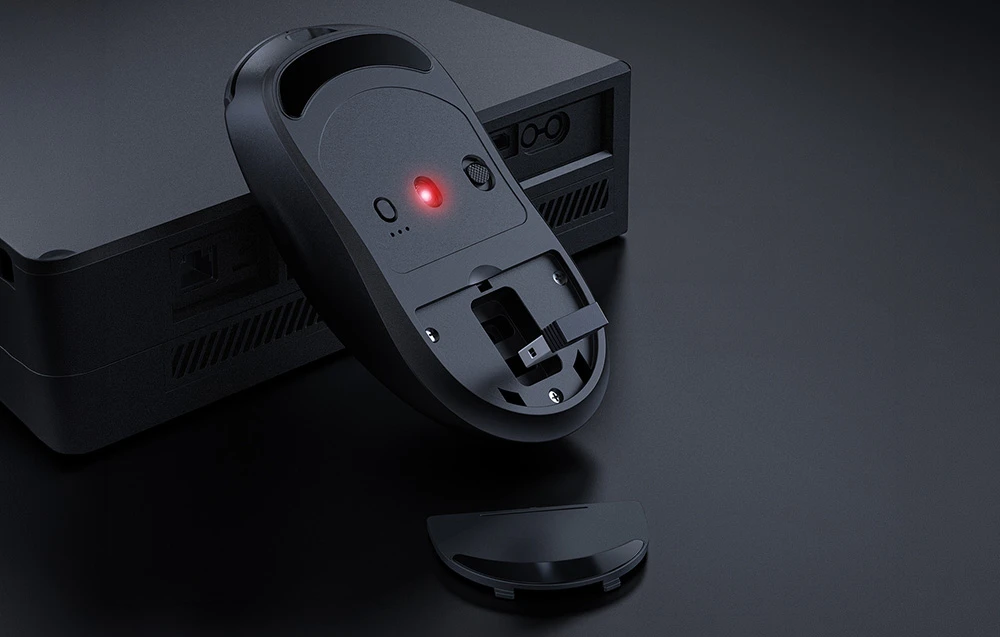 Mouse de computer cu susul în jos așezat pe un computer cu un compartiment pentru receptorul USB