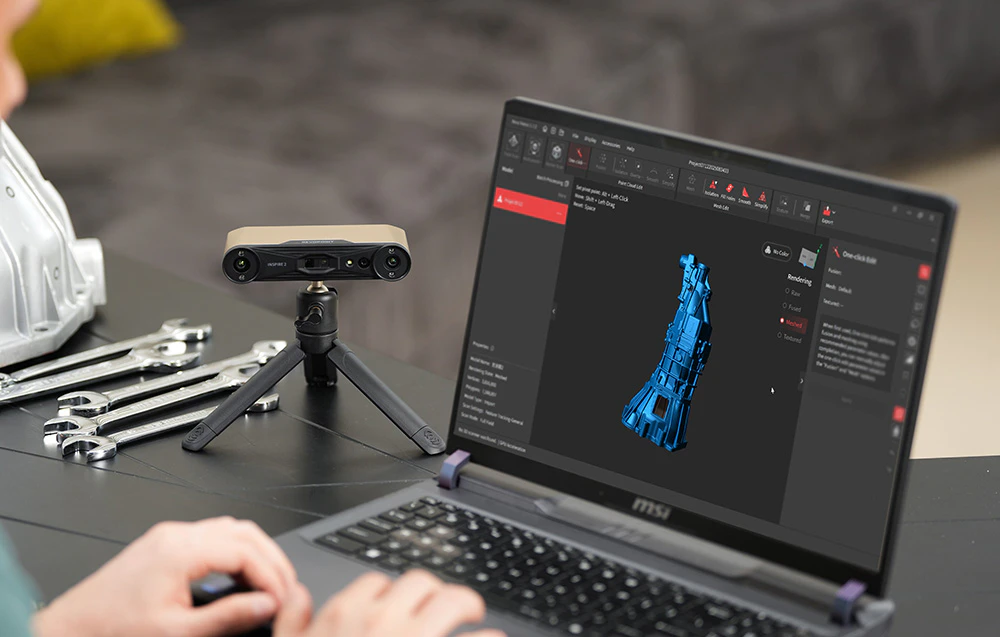 Un scaner 3D Revopoint Inspire 2 pe un trepied lângă un laptop care rulează un software 3D într-un atelier