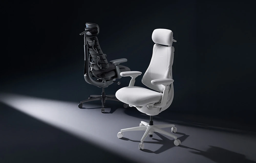 Un scaun de birou ergonomic alb în prim-plan și un scaun de birou negru vizibil în fundal, pe un fundal întunecat