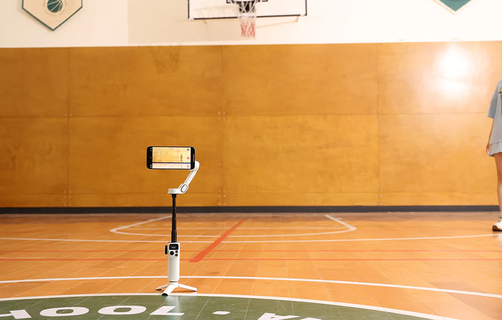Un gimbal cu un smartphone montat pe un trepied într-o sală de sport în timpul înregistrării.