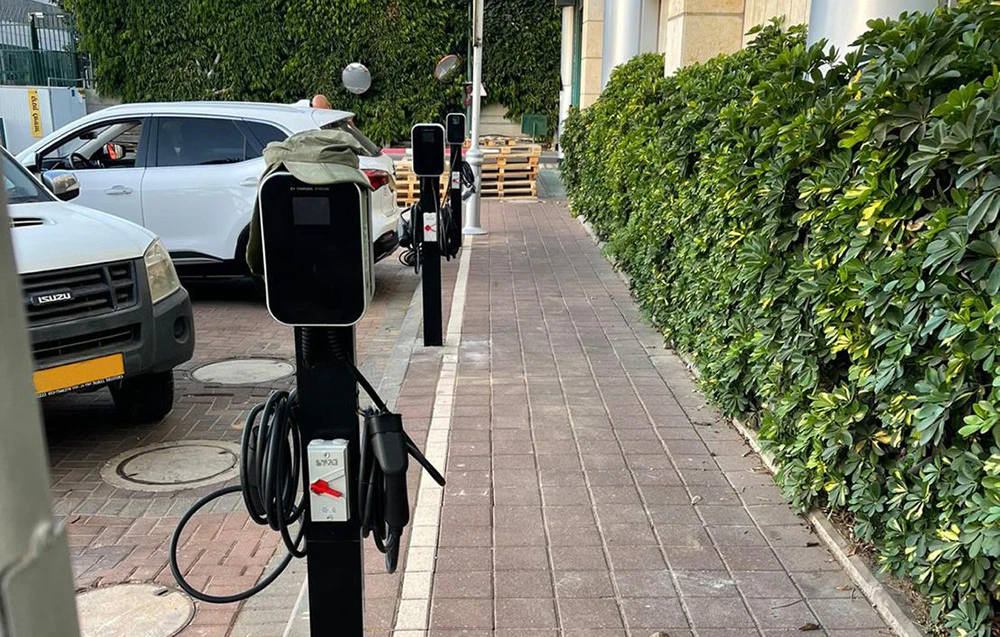 O stație de încărcare pentru mașini electrice independentă, situată lângă locurile de parcare în aer liber.