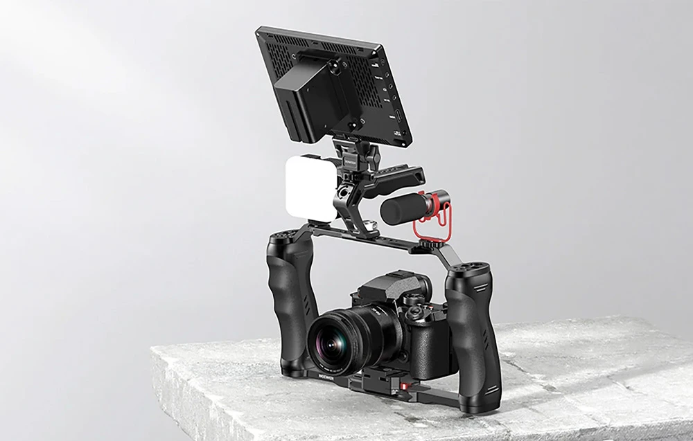 O cameră cu accesorii complete — un monitor, o lumină LED și un microfon — montată într-un mâner cu două mâini pe un blat de piatră.