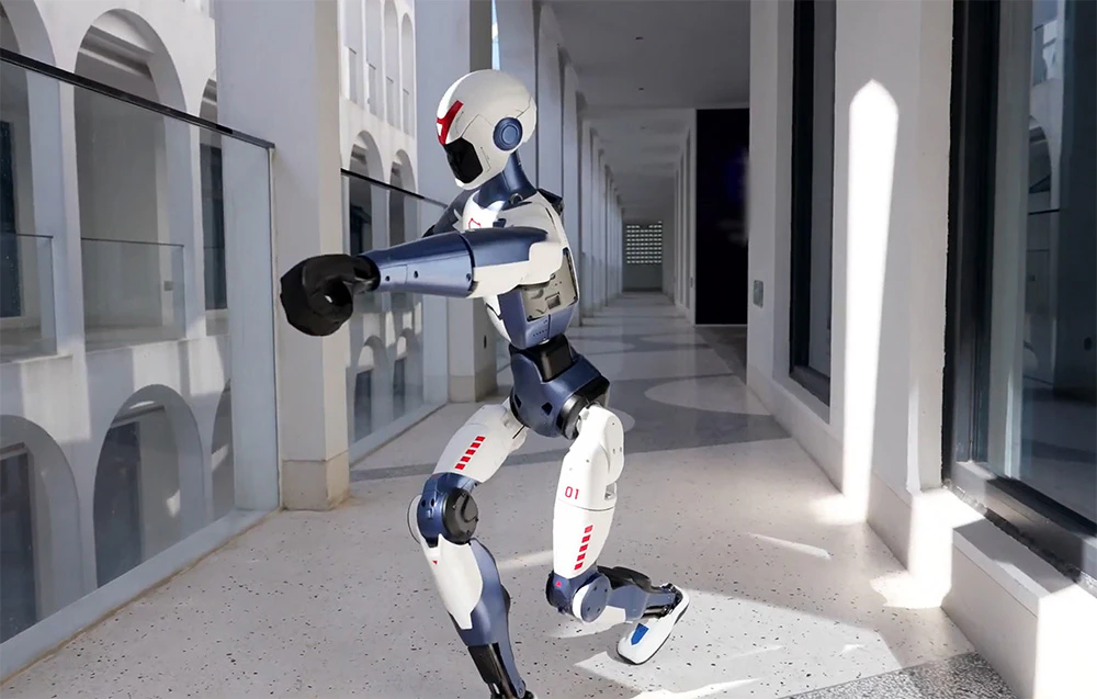 Un robot umanoid executând o eschivă dinamică într-un coridor luminos, închis cu sticlă