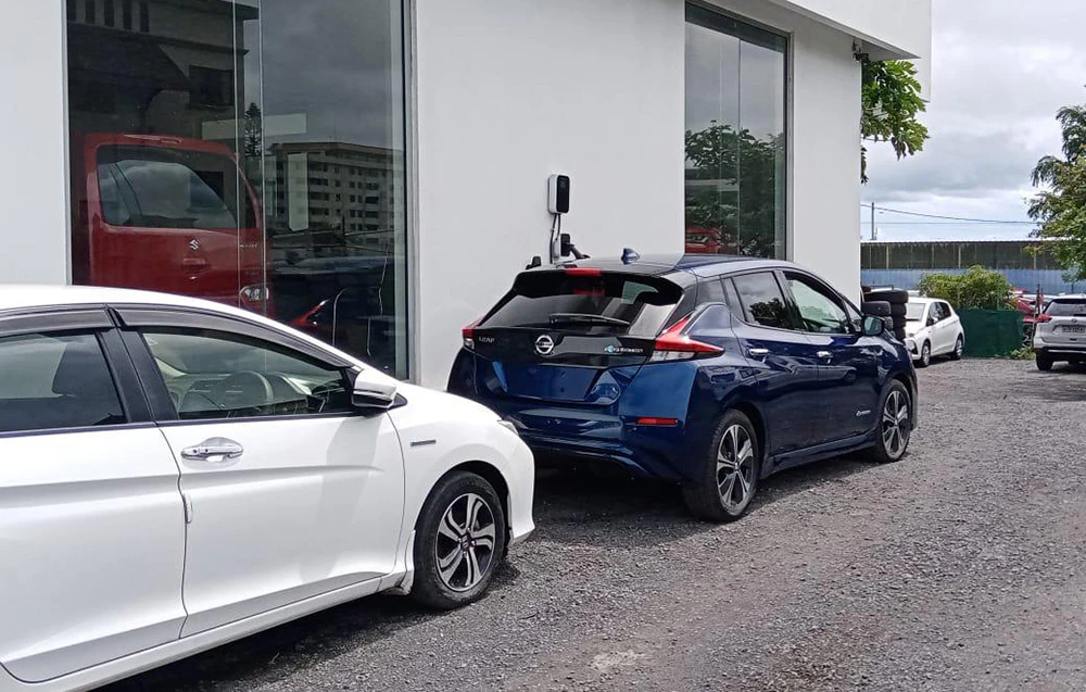 Un vehicul electric conectat la o stație de încărcare montată pe peretele unei clădiri.