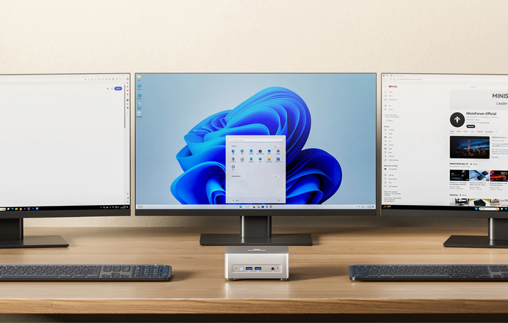 mini PC alb pe un birou lângă trei monitoare
