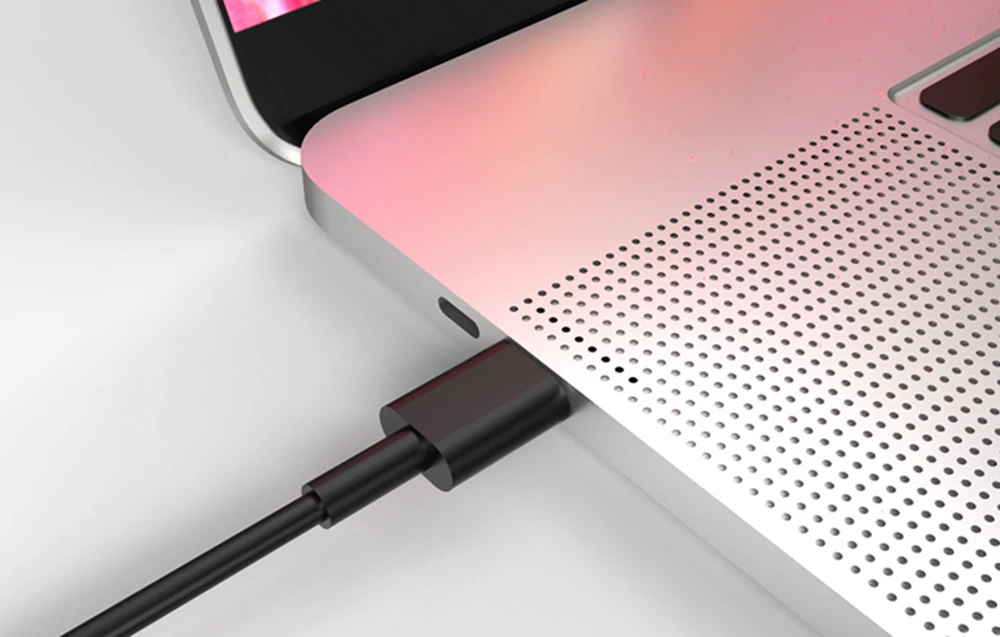 Laptop pe o masă albă cu un cablu negru conectat