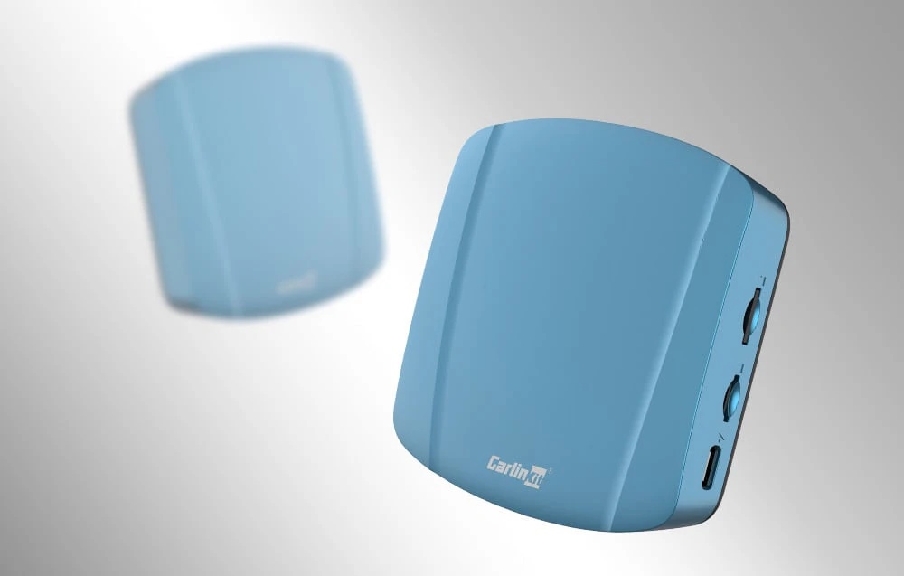Două adaptoare wireless Carlinkit TBOX ULTRA, pe un fundal deschis, unul neclar.