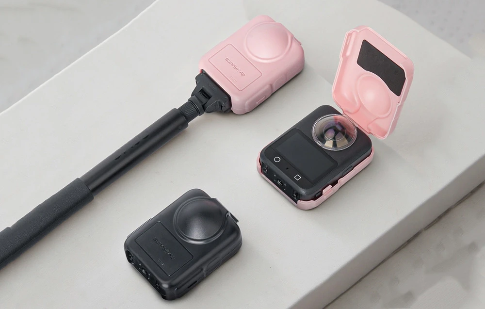 3 cameră foto în carcasă de protecție și selfie stick pe suprafață luminoasă