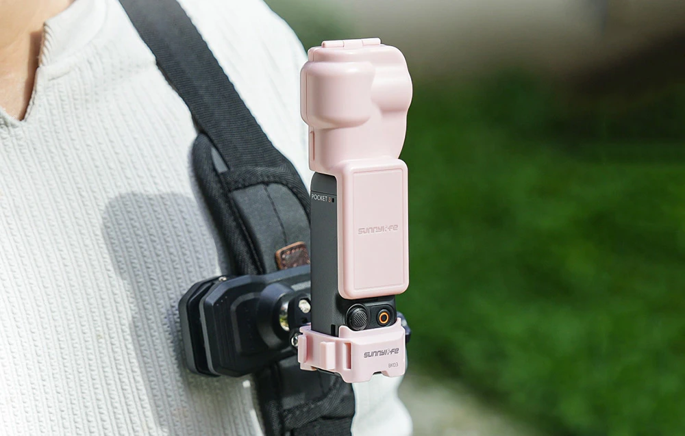Camera DJI Pocket montată într-o husă Sunnylife roz și fixată pe o curea de rucsac folosind suportul