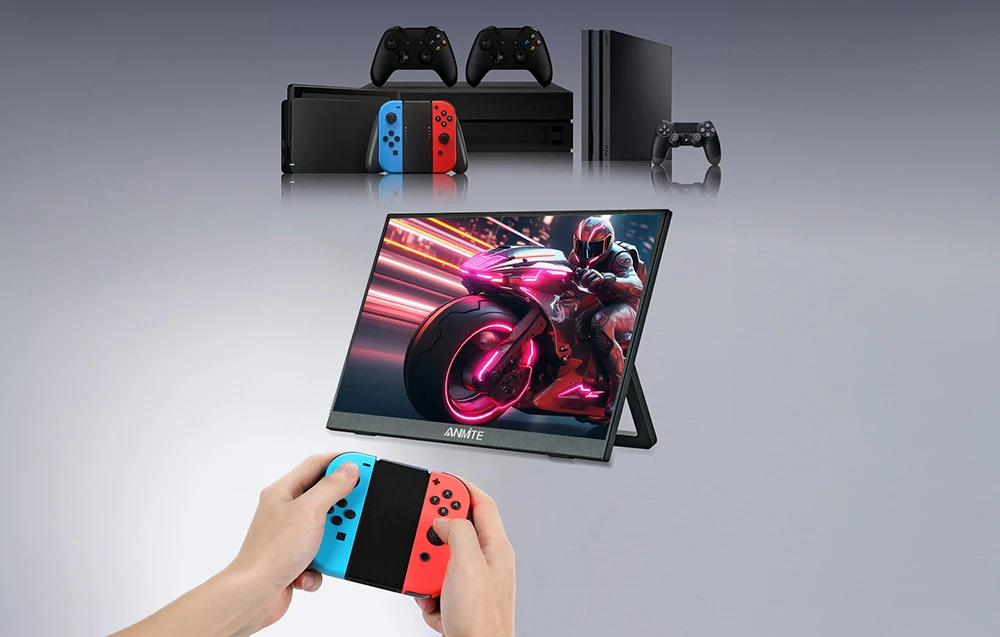 Un monitor portabil care afișează un joc de curse, cu console de jocuri deasupra lui și mâini care țin un gamepad în prim-plan.
