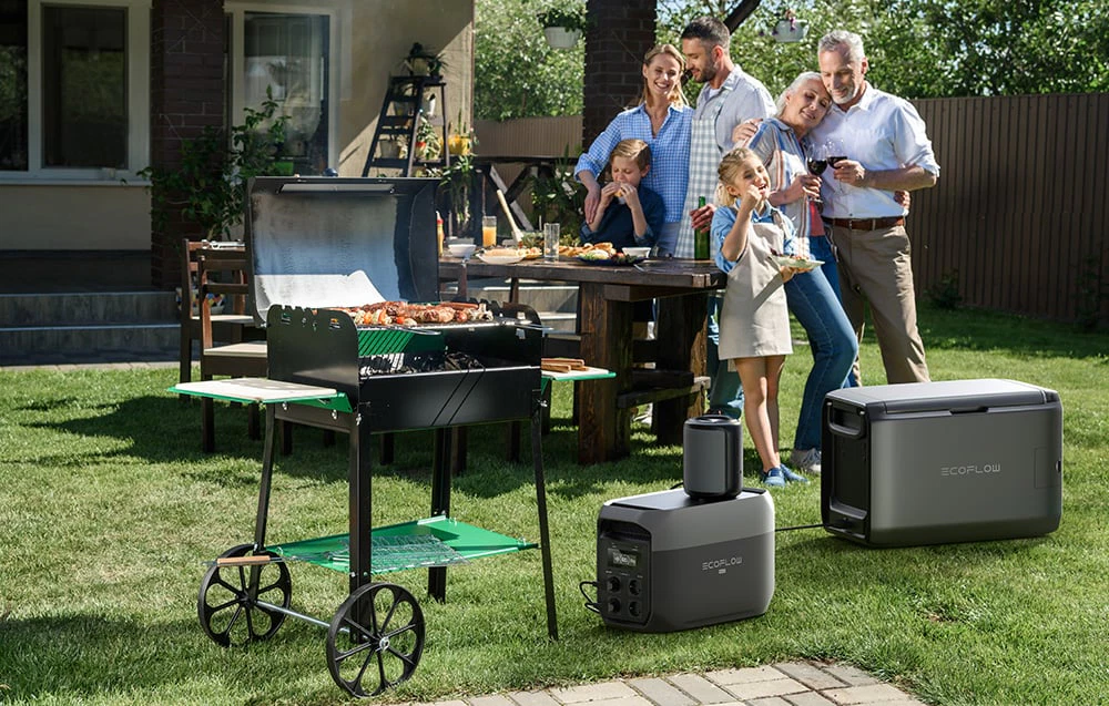 O familie la un grătar în grădină cu trei stații de alimentare EcoFlow pe iarbă.