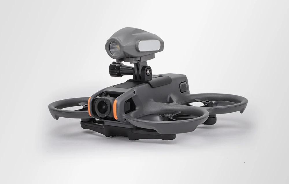 Drone gri pe un fundal deschis, cu un adaptor universal și o lampă montată în partea superioară a carcasei.