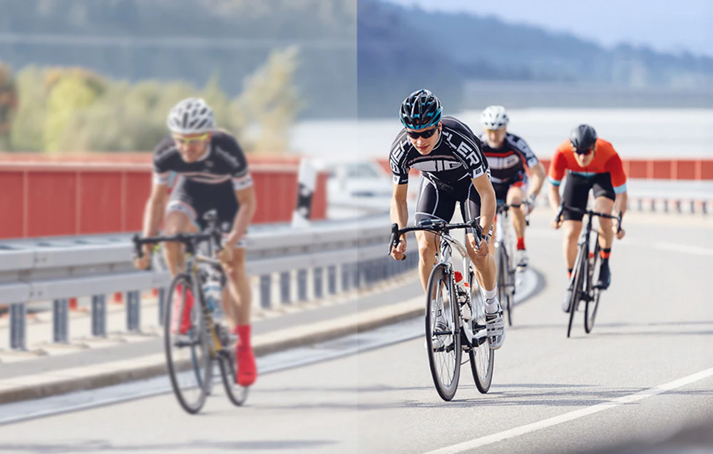 Un grup de cicliști de șosea în ținute sportive, pedalând în formație pe șosea