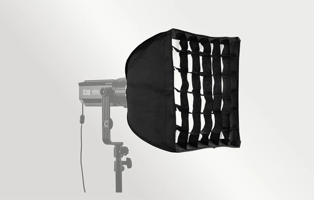 Lampa Godox S30 pe un trepied, cu un modificator de lumină negru, dreptunghiular, prevăzut cu grilă, pe un fundal de culoare deschisă.