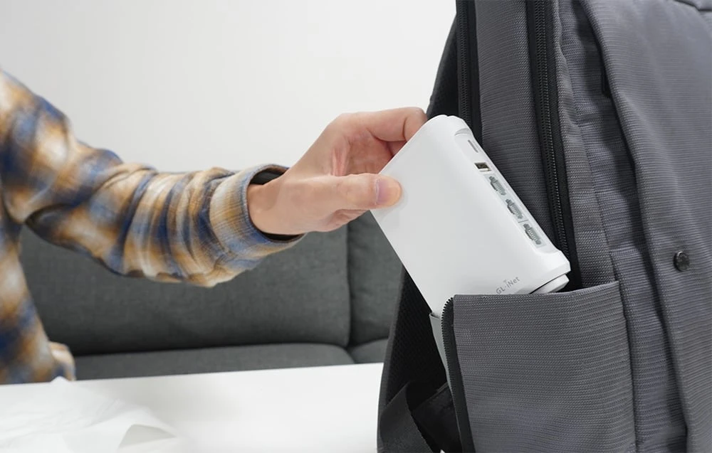 Un router GL.iNet alb introdus într-un rucsac gri