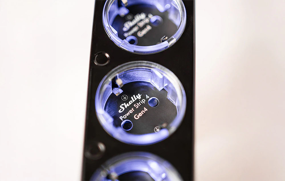 Prim plan al prizelor benzii electrice inteligente Shelly Power Strip 4 Gen4 cu iluminare de fundal LED.
