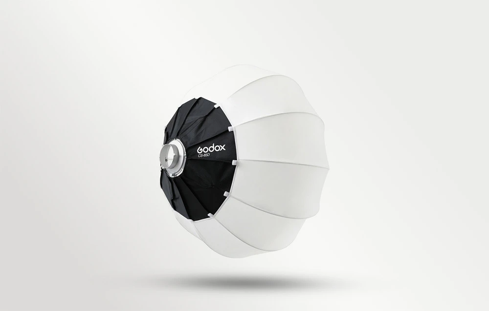 O softbox sferică rotundă, alb-negru, cu logo-ul Godox, prezentată din profil pe un fundal deschis, cu o umbră subtilă.
