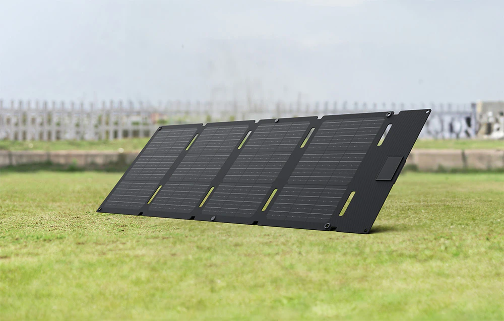 Panou solar negru desfășurat pe iarbă, cu un gard vizibil în fundal