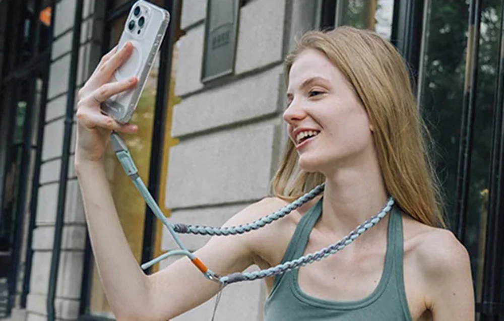 O femeie cu părul blond își face un selfie cu smartphone-ul conectat la o curea PGYTECH