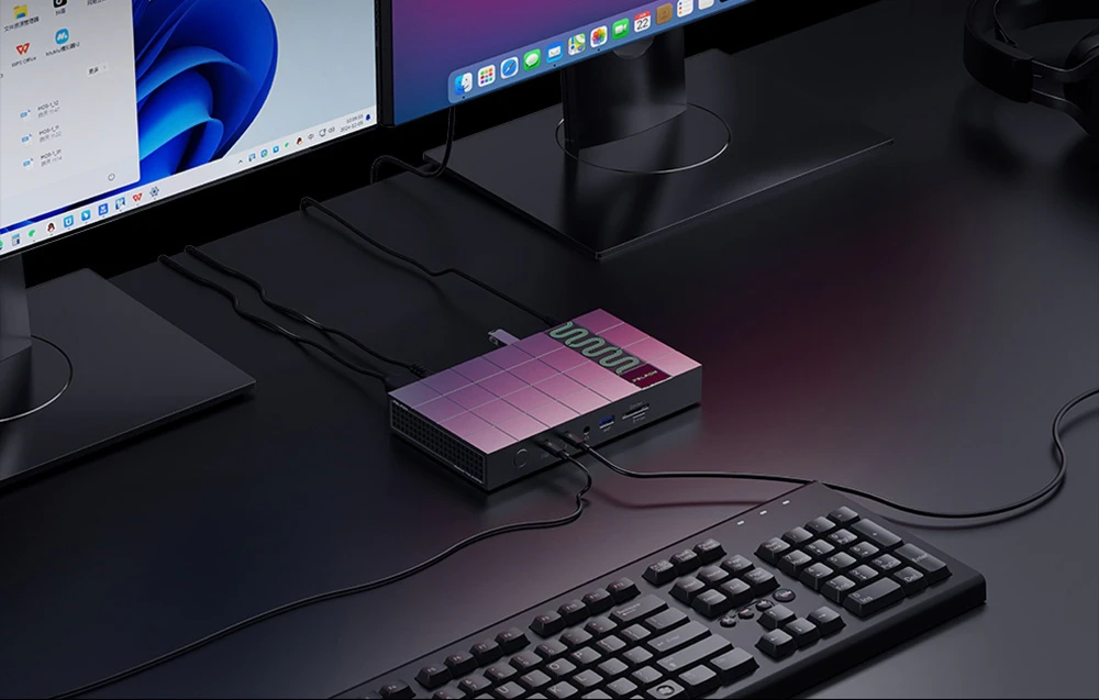 Vedere de sus a stației de andocare Peladn integrată în stația de lucru între două monitoare și o tastatură mecanică de computer. Panoul superior al dispozitivului prezintă o rețea de pătrate regulate cu un element verde, iluminat din spate