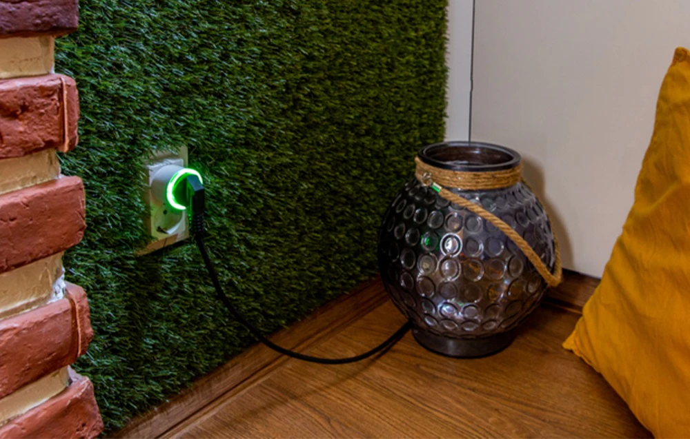 Iluminare de fundal verde a fișei Shelly Plug S conectată la contactul de la peretele de iarbă artificială