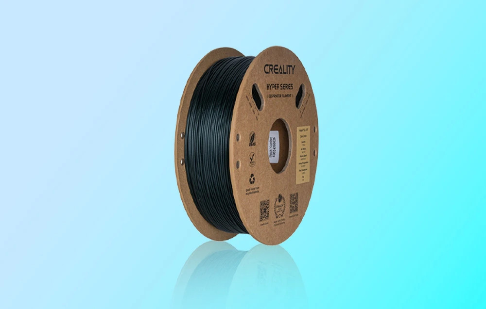 Bobină de filament Creality Hyper Series de culoare închisă pe fundal turcoaz cu reflexie