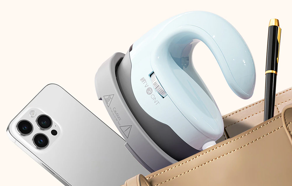 O presă termică albastru deschis așezată într-o geantă lângă un smartphone și un stilou elegant.