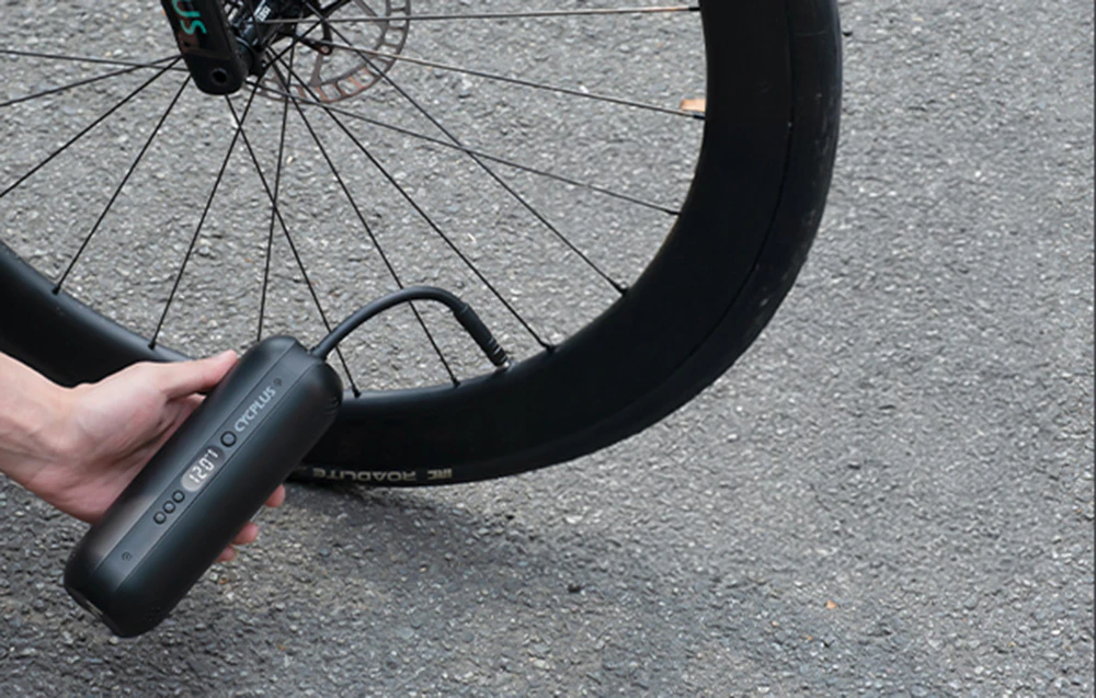 Pompa electrică Cycplus AL1 conectată la o roată de bicicletă, pompând o anvelopă
