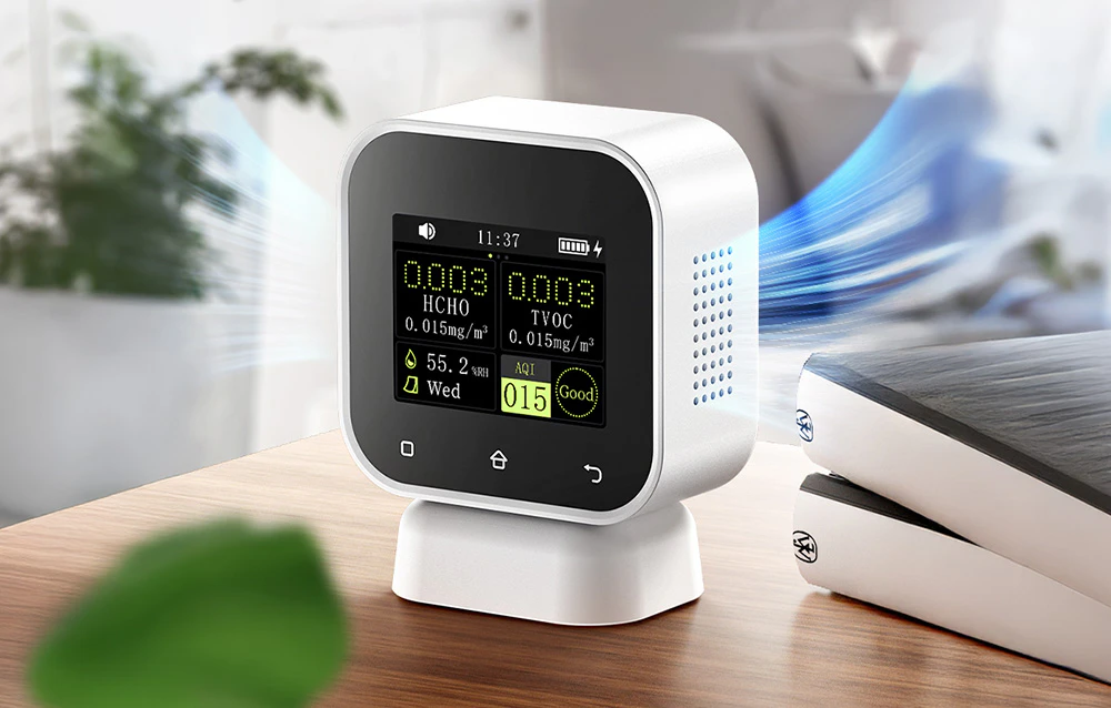Monitor de calitate a aerului pe un birou din lemn afișând parametrii HCHO, TVOC, umiditate și AQI.