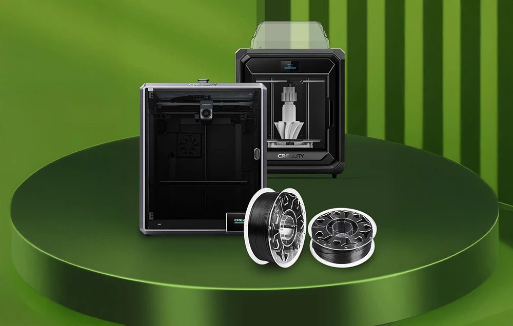 Două imprimante 3D Creality și două bobine de filament negru pe un podium verde