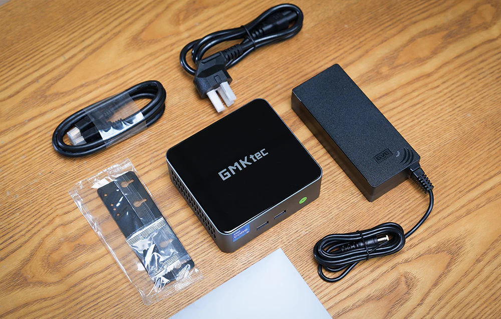 Conținutul kitului mini PC-ului GMKtec M3 Pro, incluzând sursa de alimentare, cablurile, suportul de montare și accesoriile.
