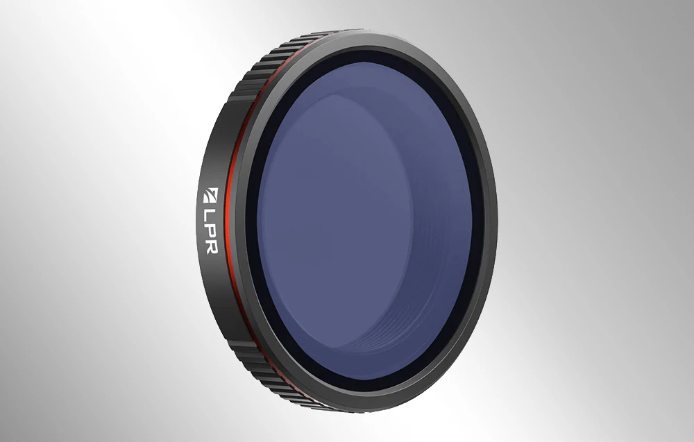 Filtru fotografic negru cu sticlă albăstruie și inscripția „LPR” pe carcasă, prezentat pe un fundal gri.