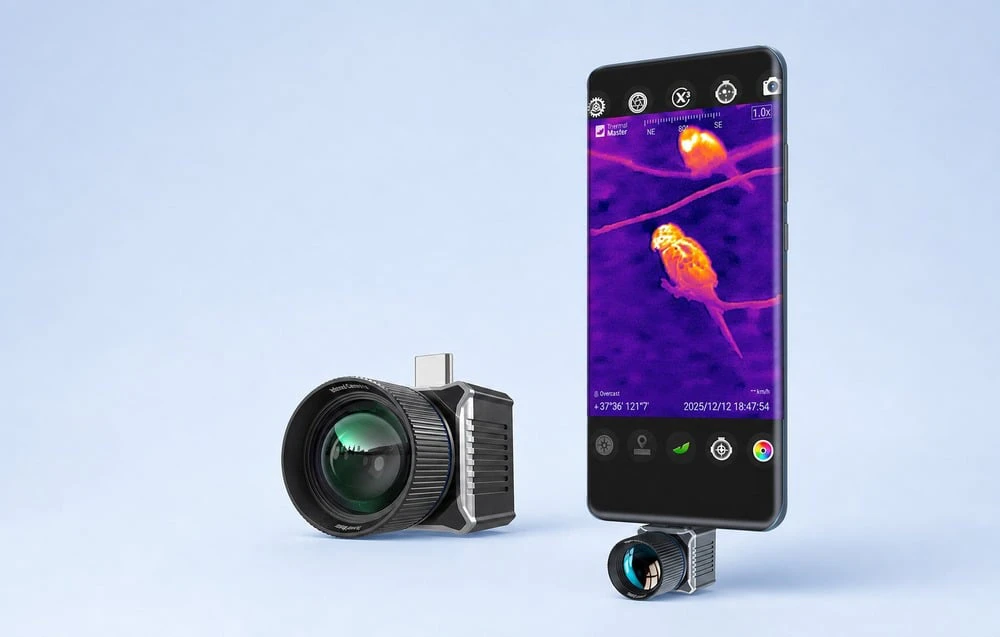 Un mic obiectiv de termoviziune conectat la portul inferior al unui smartphone, afișând o imagine termică a unei păsări pe ecranul acestuia.