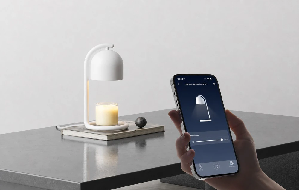 O mână care ține un smartphone cu aplicația SwitchBot, care arată glisorul setat la 100%, cu un încălzitor de lumânări alb și o lumânare parfumată într-un recipient de sticlă în fundal.