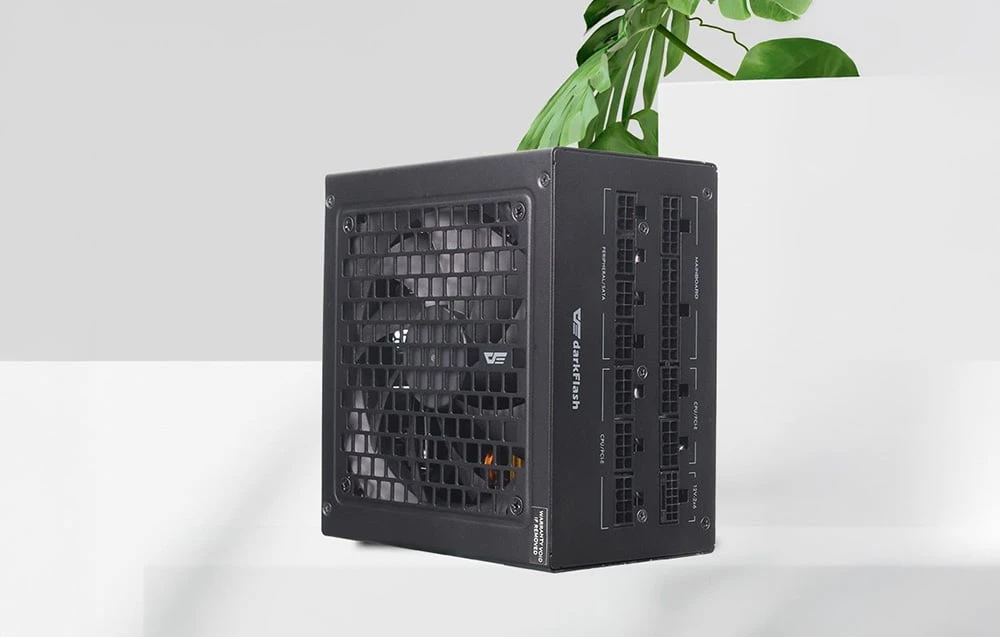 Sursă de alimentare neagră DarkFlash pe un blat alb cu o plantă verde în fundal