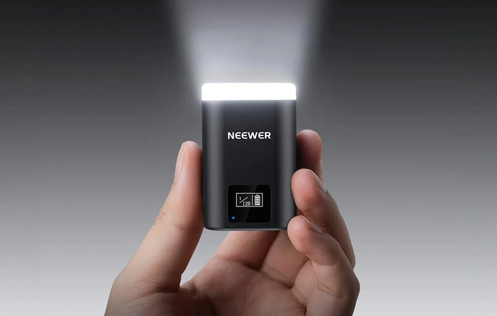Un bliț portabil miniatural negru cu lumina aprinsă și un mic ecran.