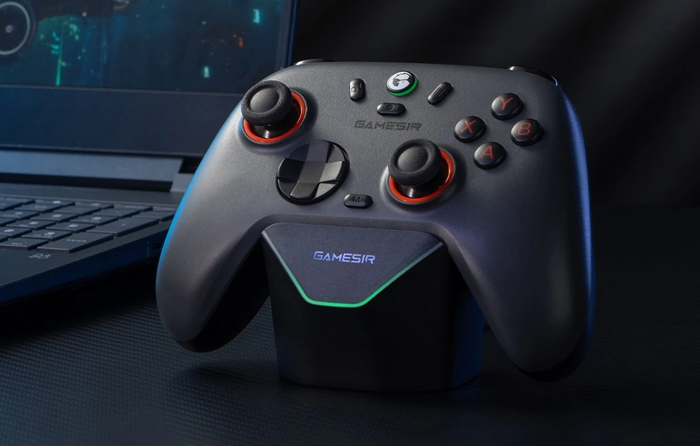 Controler GameSir gri închis cu retroiluminare roșie plasat pe stația de andocare în fața laptopului.